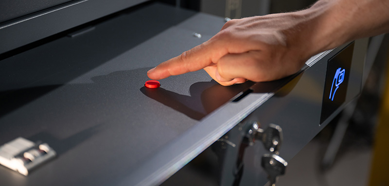 Close-up of a hand pushing a red button on a shelf of a smart vending machine.