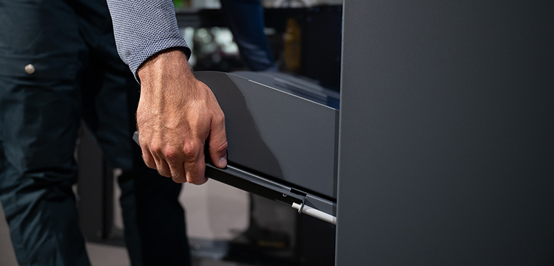 Close-up of a hand pulling out a drawer from an industrial vending machine.