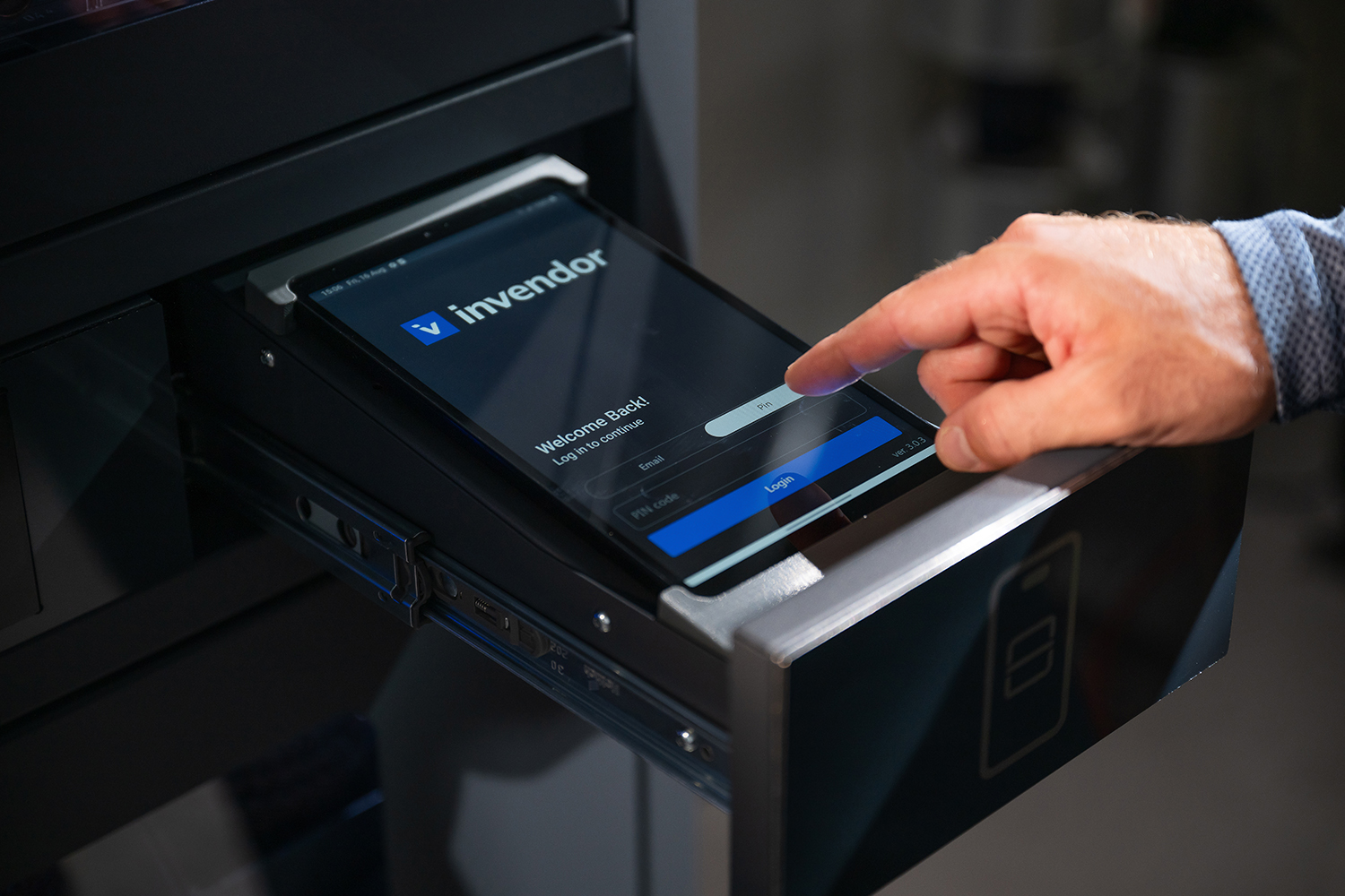 Hand interacting with a tablet running the Invendor app, inserted into a smart storage drawer.