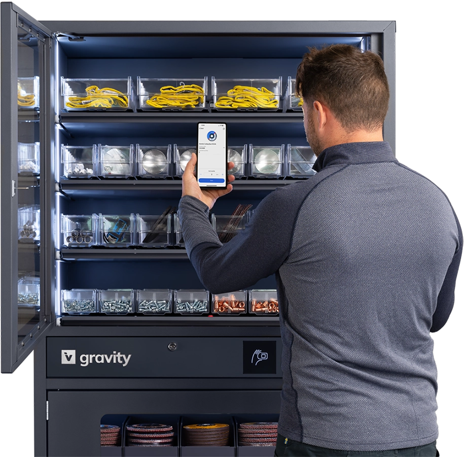 Man scanning items in an open Gravity storage cabinet using a smartphone, with organized compartments containing various tools and materials.